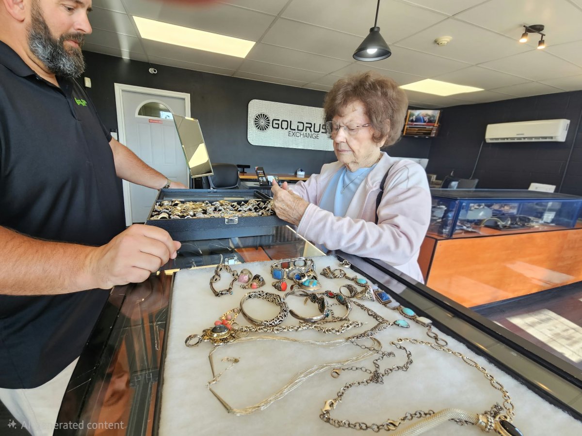 Person holding cash at a counter near a scale with gold jewelry on it
